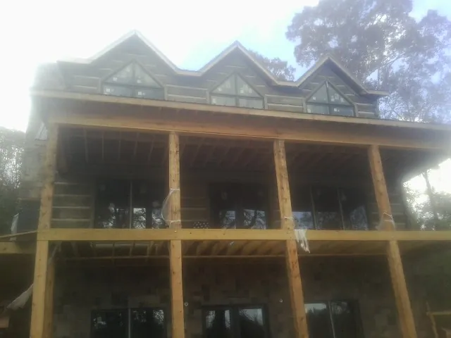 Dormers and porch framing on a large log home under construction — Roof Coating work by our crew in Elizabethville