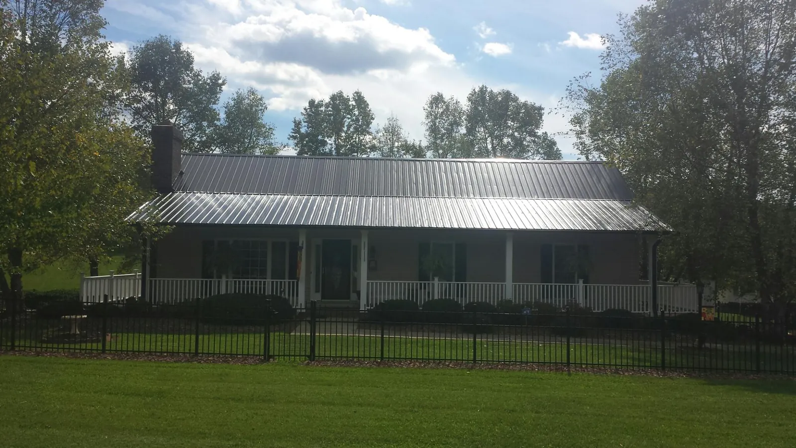 Gray metal roof on a brick ranch with a full width front porch — Gutter Guard Installation work by our crew in Elizabethville