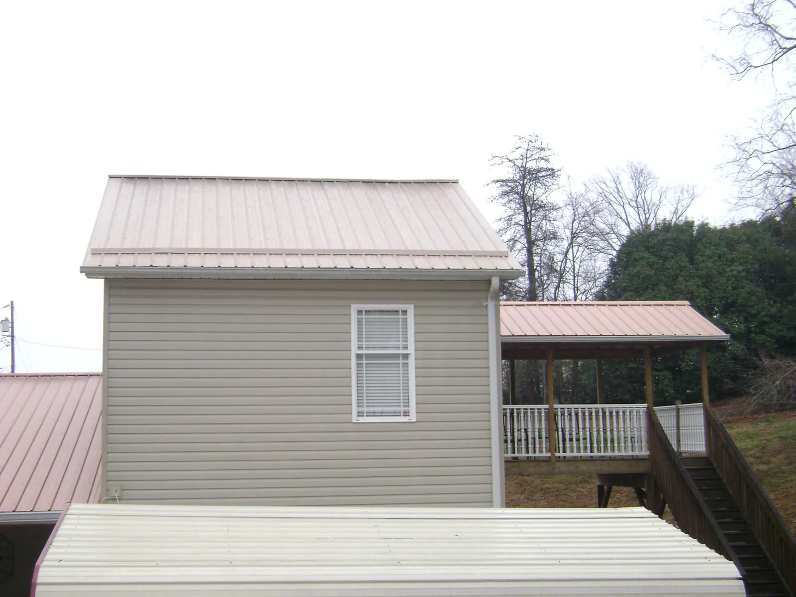 Tan metal roofs on a two story addition and attached porch, from a Roof Replacement job in Elizabethville