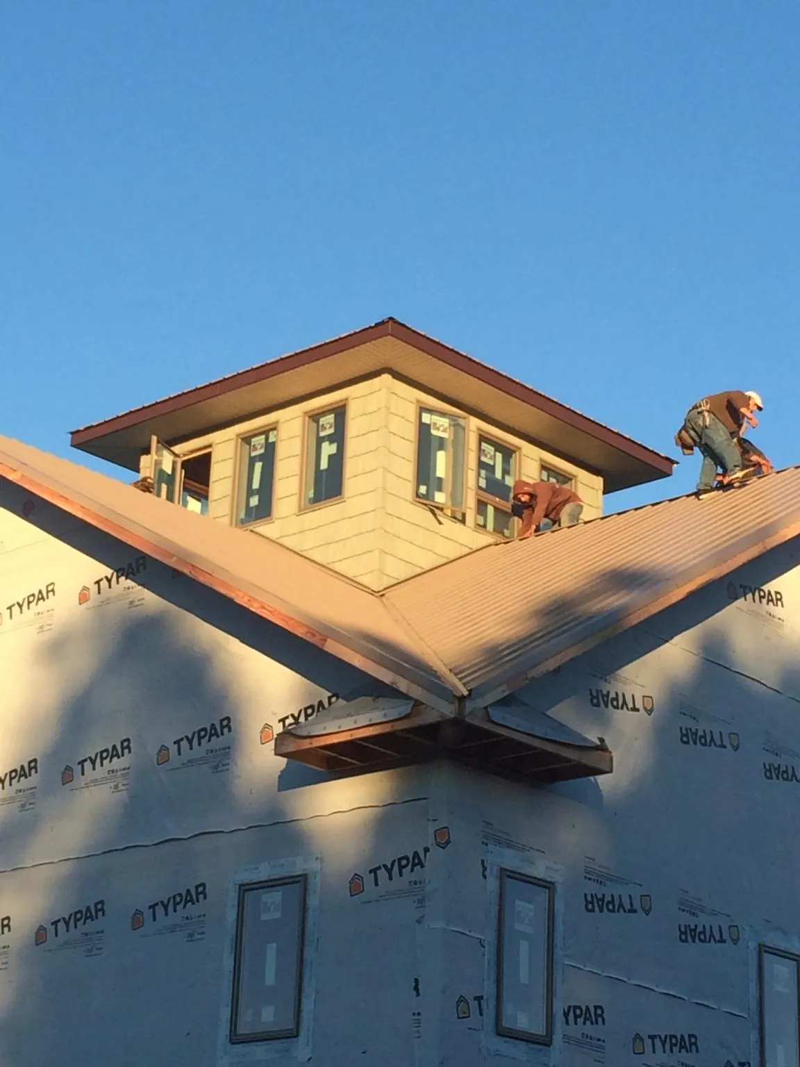 Roofers working around a rooftop cupola on a new metal roof at sunset — Roof Waterproofing in Elizabethville by Roofing Brothers